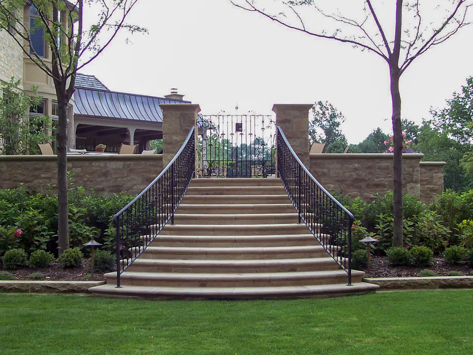 Wide formal stone steps with black railing and planting